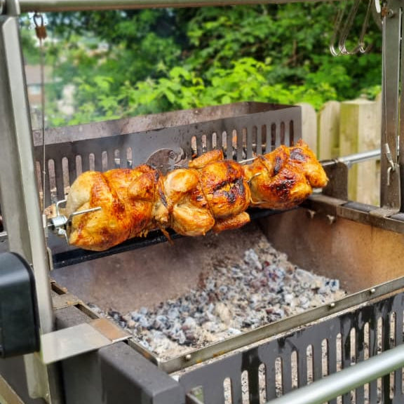 Rotisserie chickens on a large Argentinian BBQ grill 