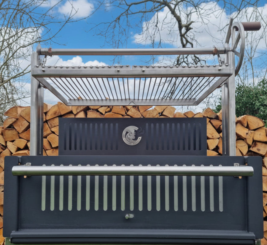 Outdoor Argentinian barbecue grill with stacked wood logs against a blue sky.