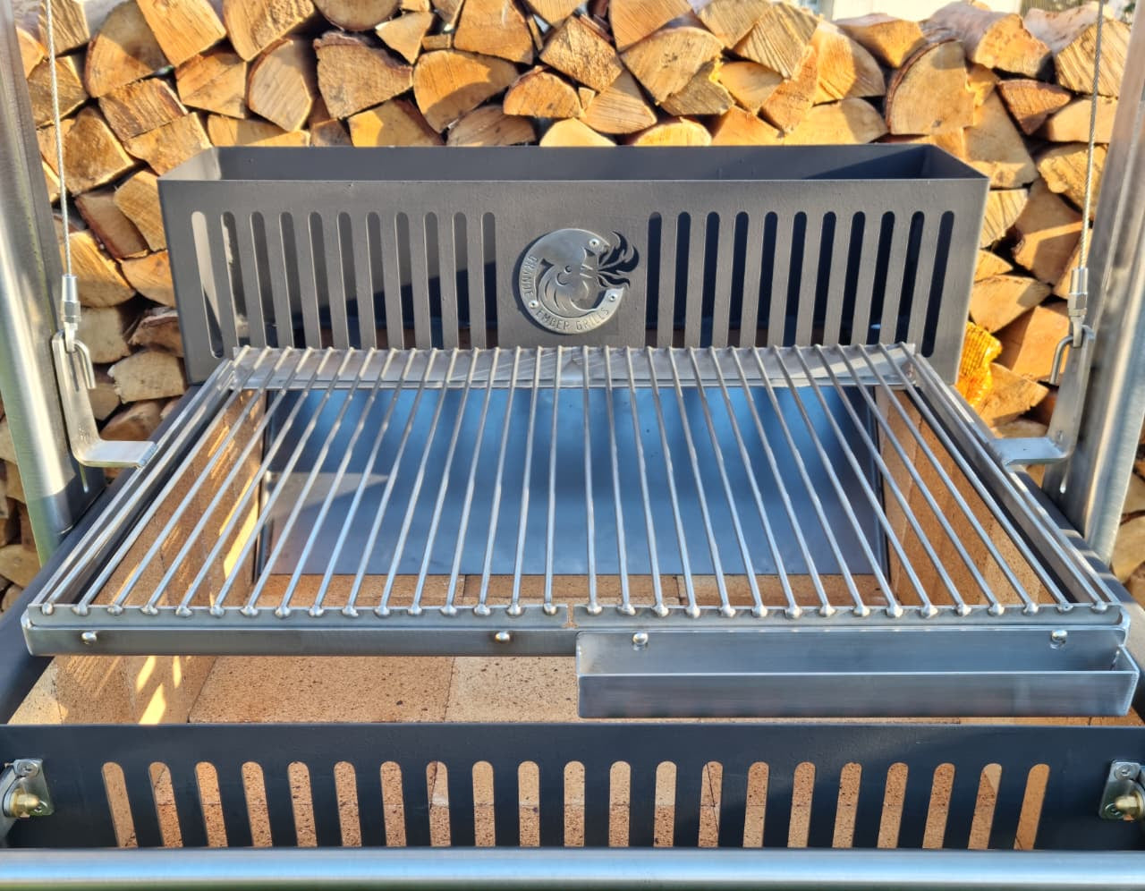 Argentinian grill with a fire pit on a stand against a background of stacked wood.