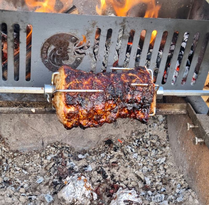 Rotisserie pork with a beautiful caramelized glaze slowly turning over hardwood coals 