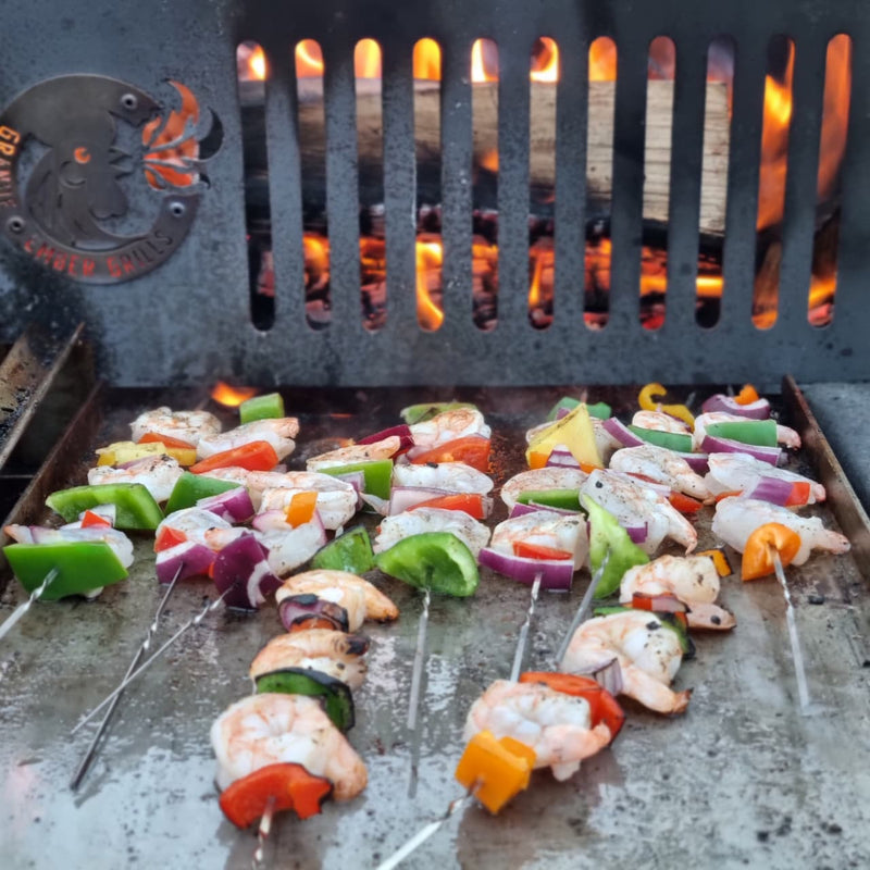 Shrimp skewers with vegetables on a stainless steel plancha